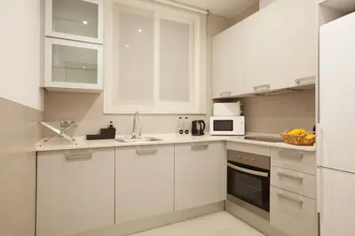 a white kitchen with white cabinets and a sink at Easysleep Borne in Barcelona