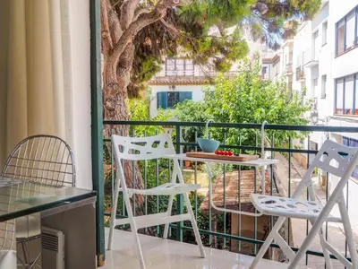 a balcony with a table and chairs and a tree at Aolani Apartment by Hello Homes Sitges in Sitges