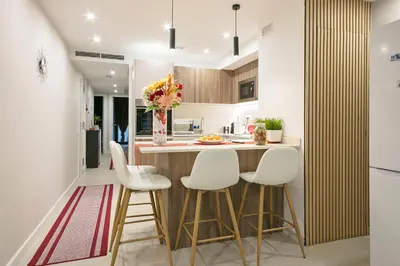 a kitchen with a bar with white stools at YOUR HOME- Apartment Camp Nou 1 in Hospitalet de Llobregat