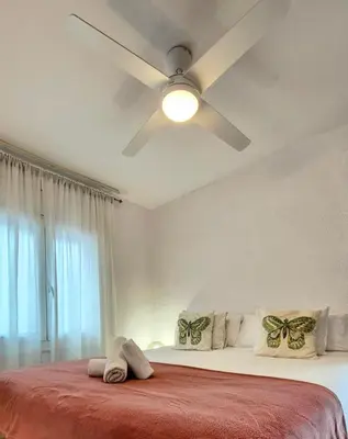 a white bedroom with a ceiling fan and a bed at Vila Sitges, big house with pool in Sitges