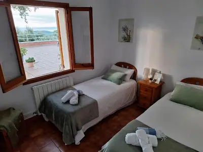 a bedroom with two beds and a window with a view at Casa Roure-4BR-Piscina privada-BBQ-Vistas Mar in Sant Cebrià de Vallalta