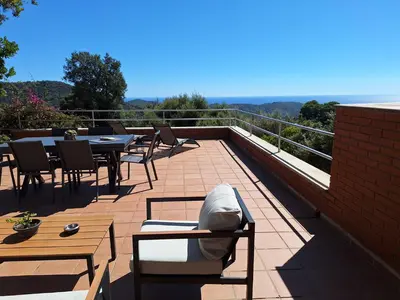 a patio with tables and chairs on a balcony at Casa Roure-4BR-Piscina privada-BBQ-Vistas Mar in Sant Cebrià de Vallalta