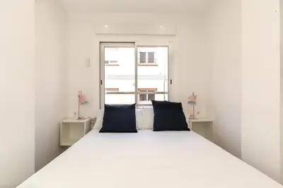 a bedroom with a white bed with two blue pillows at Picasso Suites Cornellá in Cornellà de Llobregat