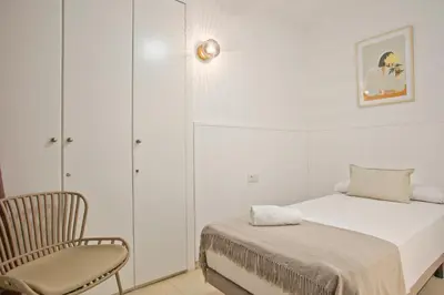a white bedroom with a bed and a chair at Anton's Downtown Apartment in Barcelona