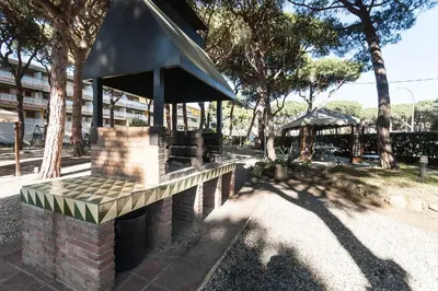 a bench in a park with trees and a building at Lets Holidays Castelldefels Diagonal Orient in Castelldefels