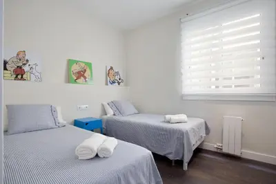 two twin beds in a room with a window at Consell de Cent Apartment in Barcelona