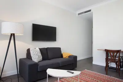 a living room with a couch and a tv on the wall at Consell de Cent Apartment in Barcelona