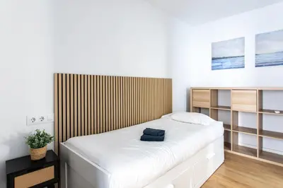a bedroom with a white bed with a wooden headboard at StayCampNou 3BR With Balcony in Hospitalet de Llobregat