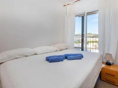 a bedroom with a bed with two blue pillows on it at Apartment Cortijo Barques by Interhome in Sitges