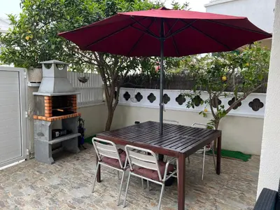 a wooden table with a red umbrella and two chairs at Apartamento Villa Caracol in Cunit