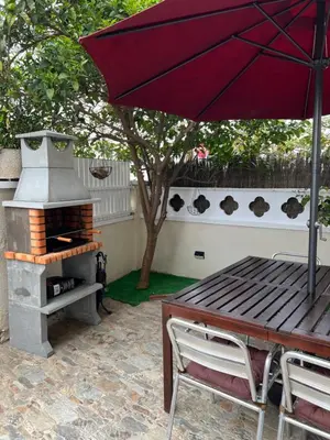 a picnic table with an umbrella and a grill at Apartamento Villa Caracol in Cunit