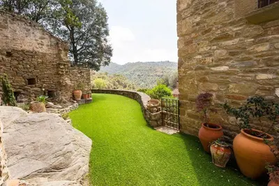 a yard with green grass next to a stone building at Masía espectacular cerca de Barcelona in Granera