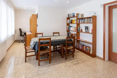 a dining room with a table and chairs and a book shelf at Niu d'Oreneta in Canet de Mar