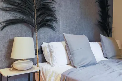 a bed with white pillows and a table with a lamp at En Ville Boutique Apartments Tamarit in Barcelona