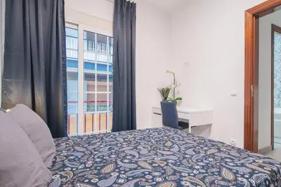 a bedroom with a bed and a desk and a window at Dega Sagrada Familia in Barcelona