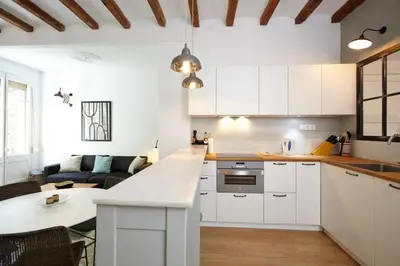 a kitchen with white cabinets and a living room at Beautiful apartment in C/Sepulveda in Barcelona