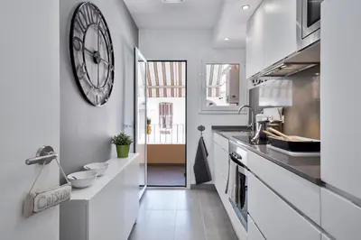 a white kitchen with a large clock on the wall at Charming & Quiet Park Guell Apartment in Barcelona