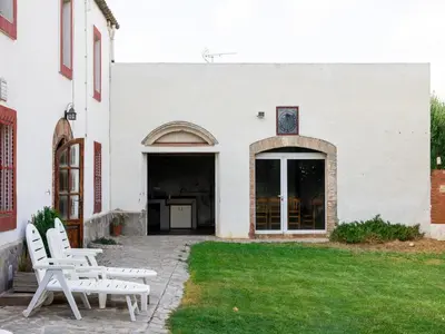 two white benches sitting outside of a white building at Can Teulera in San Martín Sarroca