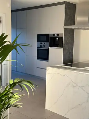 a kitchen with white cabinets and a marble counter top at Shome in Vilanova i la Geltrú