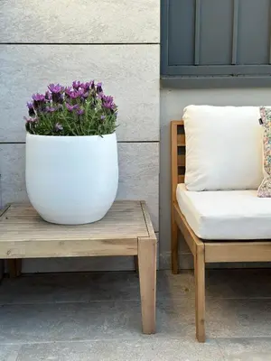 a white pot of flowers sitting on a table next to a bench at Shome in Vilanova i la Geltrú