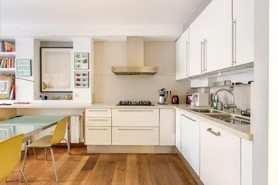 a kitchen with white cabinets and a table at ArtlifeBCN Fira Apartment in Barcelona