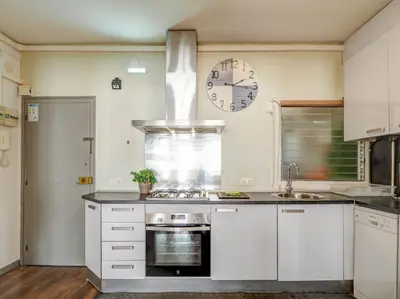 a kitchen with white cabinets and a clock on the wall at Espalter White by Hello Homes Sitges in Sitges