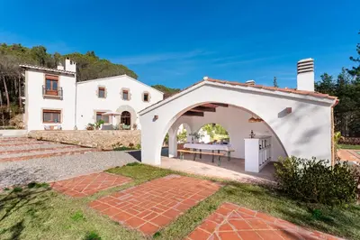 an external view of a white house with an archway at El Huerto - Großzügiges Appartment in Katalanischer Masia in Sant Iscle de Vallalta