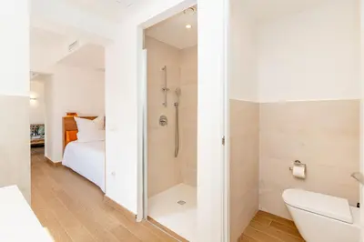 a white bathroom with a shower and a bed at Ginkgo - Familienfreundliches Appartment in Katalanischer Masia in Sant Iscle de Vallalta