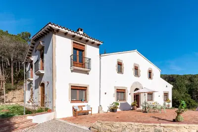 a large white house with a patio at Gallinero - Familienfreundliches Appartment in Katalanischer Masia in Sant Iscle de Vallalta