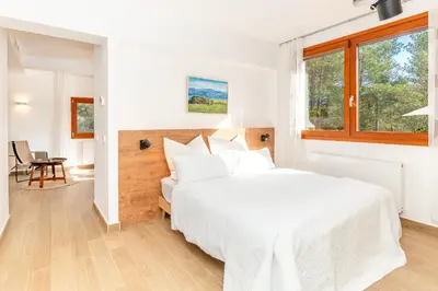 a white bedroom with a large bed and a window at Gallinero - Familienfreundliches Appartment in Katalanischer Masia in Sant Iscle de Vallalta