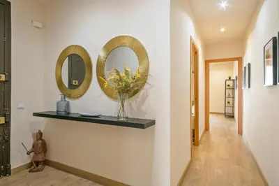 a hallway with two mirrors and a vase of flowers on a shelf at Alcam Galileu P in Barcelona