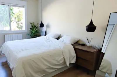 a bedroom with a white bed and a wooden dresser at Design Apartment with Sea View in Castelldefels
