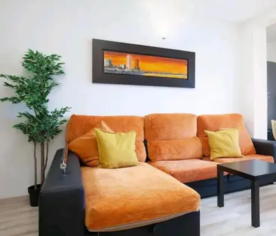 an orange couch in a living room with a painting on the wall at Centric Apartment Gran Via 5 in Hospitalet de Llobregat