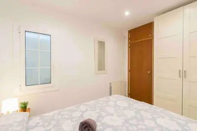 a white bedroom with a bed and a window at BEACHFRONT APARTMENT Castelldefels in Castelldefels