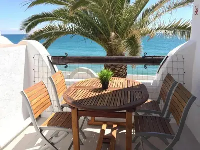 a table and chairs on a balcony with a palm tree at Apartment Raco in Vilanova i la Geltrú
