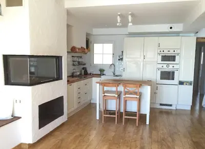 a kitchen with white cabinets and a wooden table at Apartment Raco in Vilanova i la Geltrú