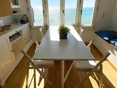 a table and chairs in a kitchen with the ocean at Apartment Raco in Vilanova i la Geltrú