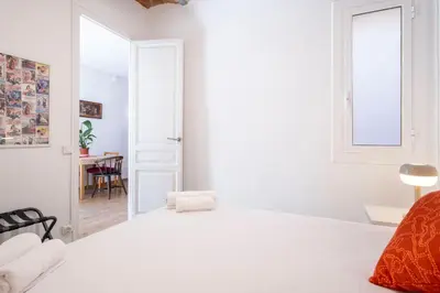 a white bedroom with a bed and a table at Centric Molino Theatre 1-1 in Barcelona