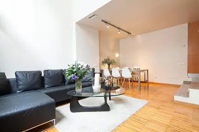 a living room with a black leather couch and a table at My Space Emirates - Charming Duplex in Barcelona ideal for Families or Friends in Barcelona
