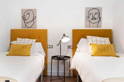 two beds with yellow pillows in a bedroom at Enamorats Glorias in Barcelona