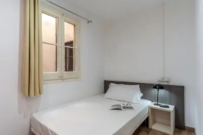 a white bedroom with a bed and a window at AB Margarit Apartments in Barcelona