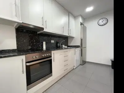 a kitchen with white cabinets and a clock on the wall at Apartment Picasso in Vilanova i la Geltrú