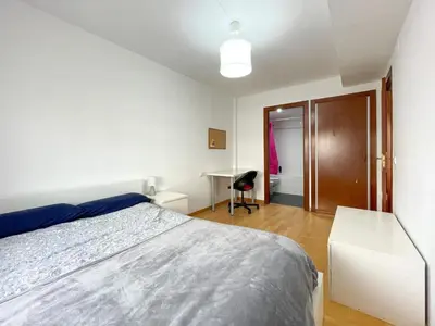 a white bedroom with a bed and a desk at Apartment Picasso in Vilanova i la Geltrú