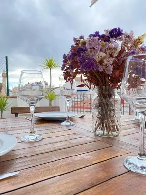 a table with glasses and a vase of purple flowers at Ático con terraza! Ideal para vivir Sitges todo el año in Sitges