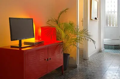 a red dresser with a monitor and a plant on it at Casa Tortilla Sant Antoni in Barcelona
