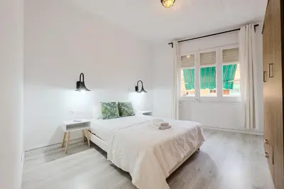 a white bedroom with a bed and a window at Bed&BCN Mas Apartments in Hospitalet de Llobregat