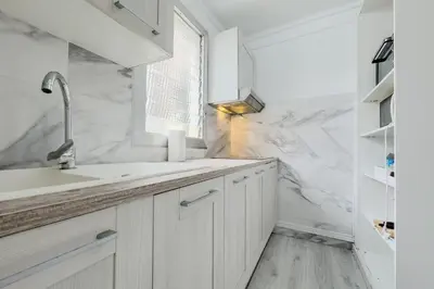 a white kitchen with a sink and a window at Bed&BCN Mas Apartments in Hospitalet de Llobregat