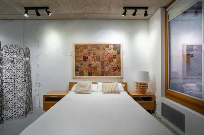 a bedroom with a large bed and a painting on the wall at Loft estilo industrial en Esplugues - 15 min de Barcelona in Esplugues de Llobregat