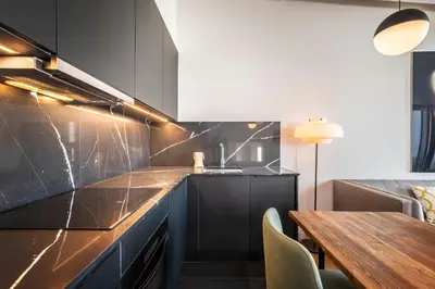 a kitchen with black cabinets and a wooden table at CATERINA Correos in Barcelona