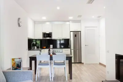 a kitchen with white cabinets and a table and chairs at 2512 - AB Comte dUrgell P-II in Barcelona